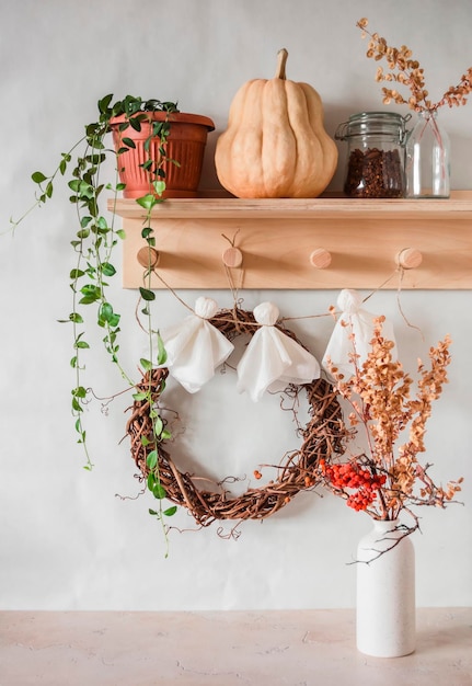 Accogliente interno del corridoio appendiabiti in legno con ghirlanda di fiori di zucca e uva e ghirlanda di fantasmi di carta fatta in casa