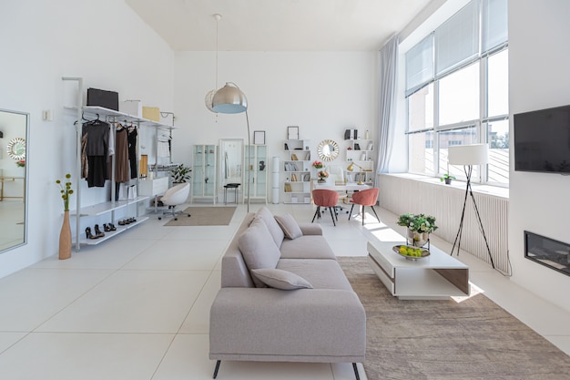 Уютный роскошный современный интерьер однокомнатной квартиры в экстра-белых тонах с модной дорогой мебелью в стиле минимализма.