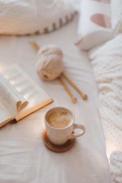 Cozy morning composition with a coffee cup and a book in bed