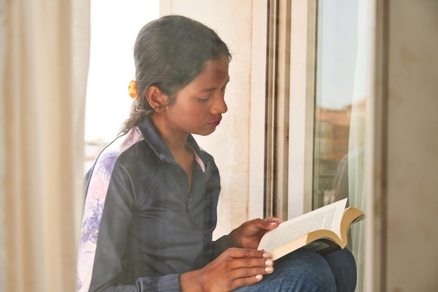 Cozy morning read by the window with a lovely Indian woman