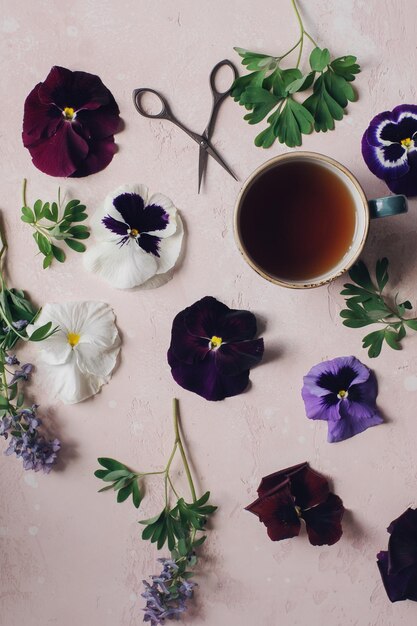 Cozy morning with cup of tea and colorful viola flowers top view