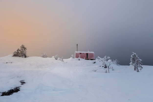 Cozy northern guest house on a snowy hill at dawn Cabin in winter dawn Lonely house on a hilltop in the cool morning