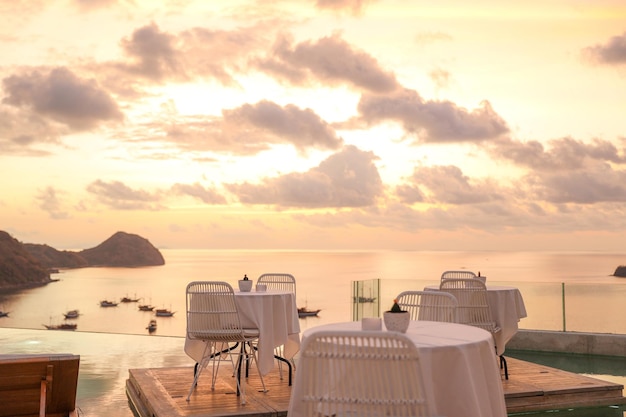 Cozy and romantic cafe with table and chairs on rooftop with sea and sunset view