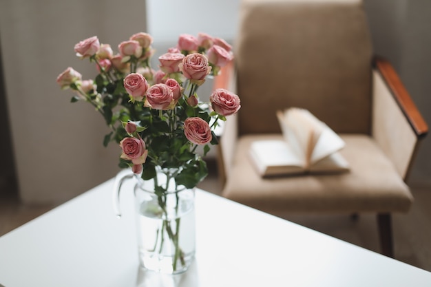 Cozy room with flowers in a vase, armchair and a book