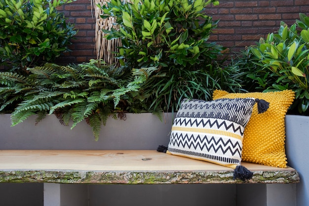 居心地の良い庭の座席の緑の植物とモダンな装飾のカラフルな枕と居心地の良い座席木製ソファ
