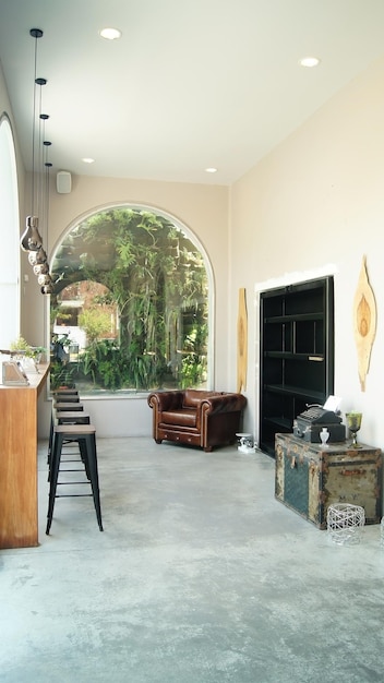 Cozy space with antique furniture at the back an arched window\
and greenery behind old typewriter