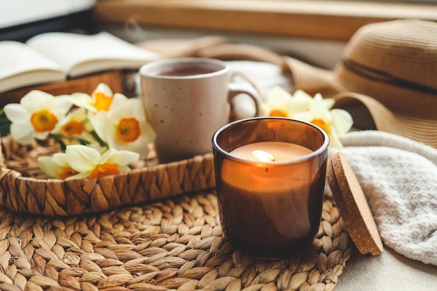 Cozy spring composition burning candle daffodils and hat