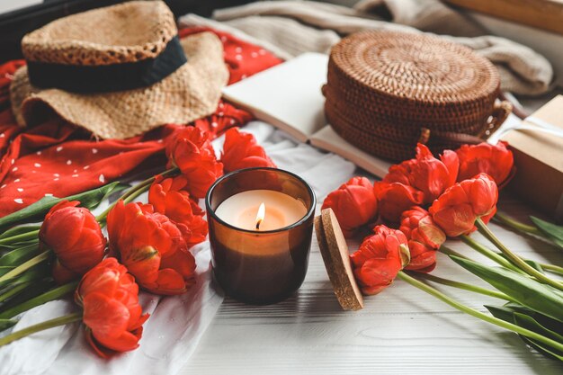 Cozy spring composition burning candle peonies and hat