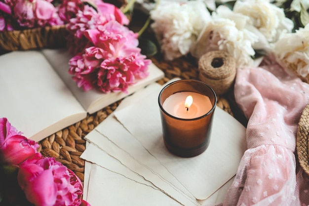 Cozy spring composition burning candle peonies and hat