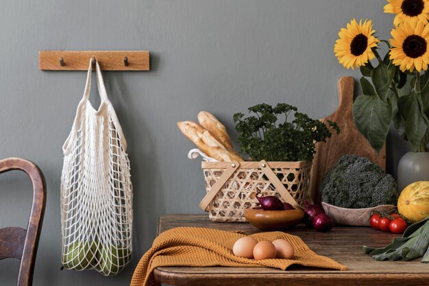 Cozy and stylish composition of creative dining room with mock up poter frame, wooden consola, sunflowers and personal accessories. Grey wall. Beautiful and sunny morning. Template.