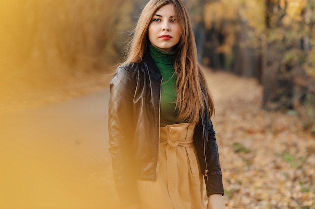 Cozy stylish young girl walk at autumn park