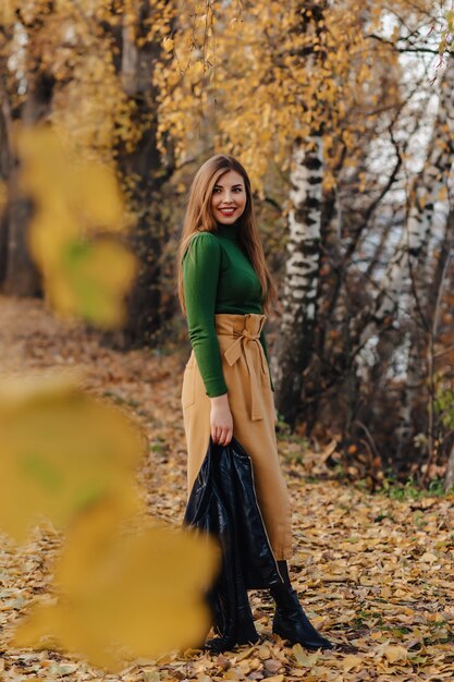 Cozy stylish young girl walk at autumn park