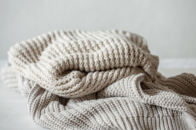 Cozy and warm knitted sweaters in pastel colors close-up.