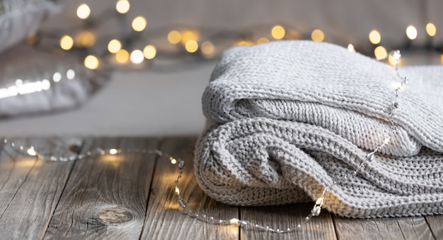 Cozy winter composition with a stack of knitted items on a blurred background with bokeh, copy space.