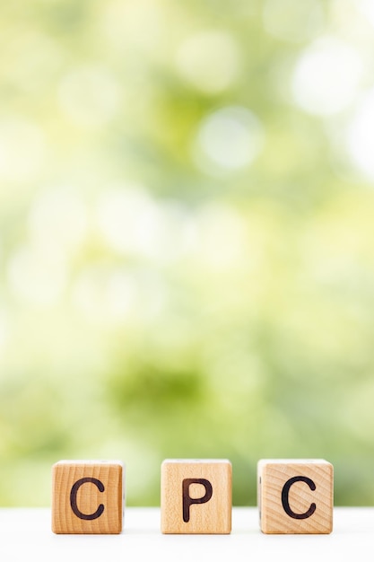 Cpc word is written on wooden cubes on a green summer background closeup of wooden elements