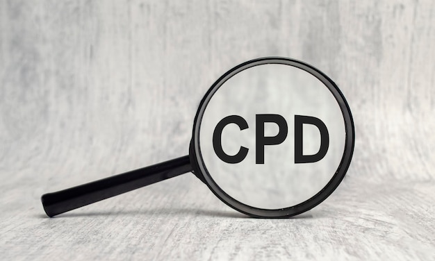 CPD word on magnifier on wooden background