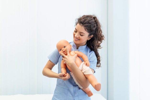 Cpr practitioner examining airway passages on infant dummy\
model dummy lays on table and two doctors practice first aid