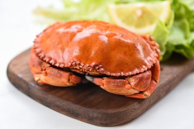 Crab cooked steam or boiled with lemon and lettuce salad vegetable on wooden board in a restaurant - Fresh seafood stone crab