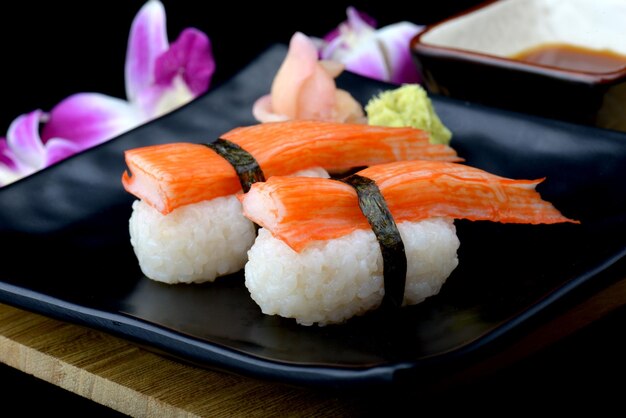 Crab stick sushi or Japanese kani sushi set on black plate with wasabi and sushi sauce with flash lighting.