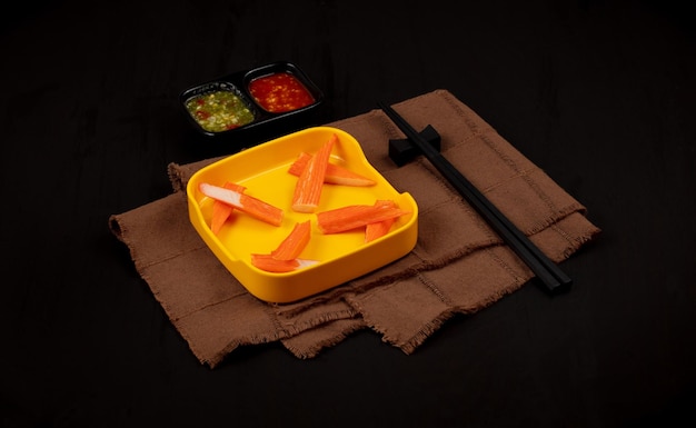 crab stick on yellow plate on black background