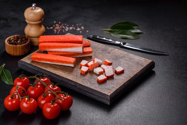 Crab sticks on a cutting Board with a knife On black concrete background