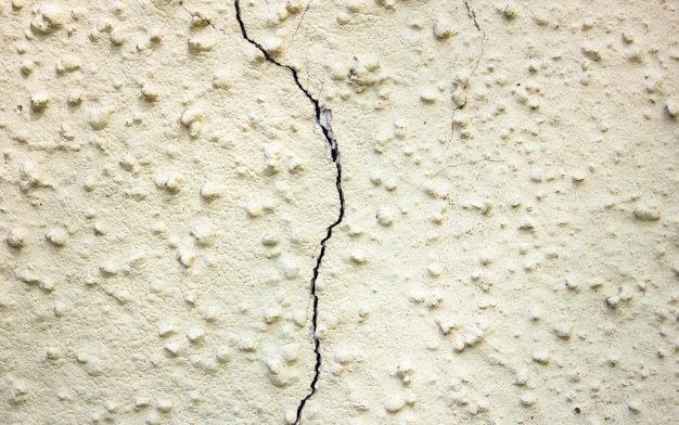 Crack on a beige yellow plaster wall Cracked plaster Damaged wall