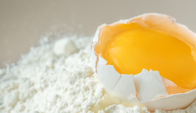 Cracked chicken egg with yolk on white flour