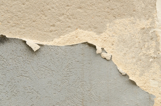 Cracked concrete wall with old layers of paint. 