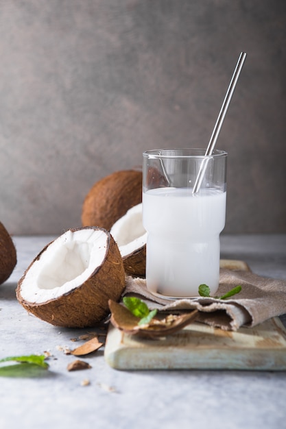 Photo cracked fresh coconut, milk  and slice nut on concrete background, space for text food ingredients, healthy lifestyle, paradise