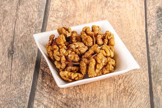 Cracked unshelled walnut nuts in the bowl