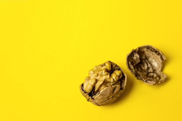 Cracked walnut on yellow background. close-up, copy space
