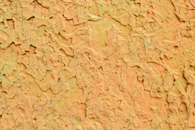 Cracked yellow textured paint on the plaster. 