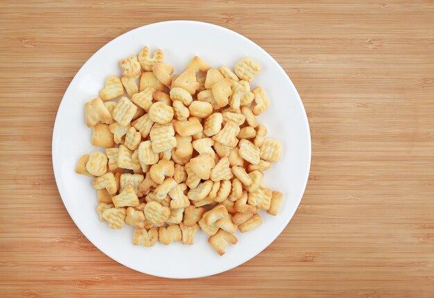 Cracker or Cookie ABC letter alphabet in white plate on wooden background with copy space.