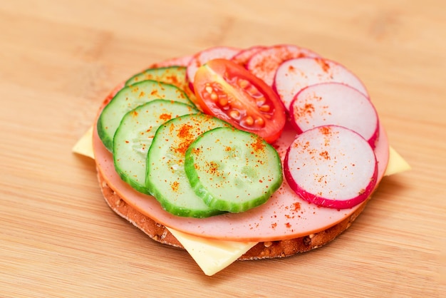 Cracker sandwich with fresh cucumber cheese sausage radish and tomato