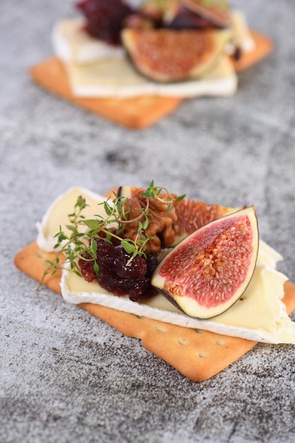 Cracker with a slice of camembert jam figs and nuts