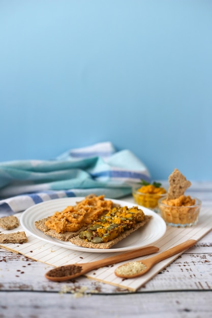 Crackers with chickpea paste on blue background. Sandwiches with hummus. Vegetarian lenten food