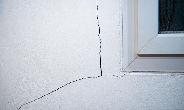 Cracks on the wall The crack in the cement wall at the window sill caused by the subsidence of the ground causing a slit at an oblique angle