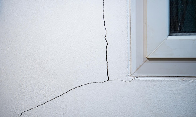 Photo cracks on the wall the crack in the cement wall at the window sill caused by the subsidence of the ground causing a slit at an oblique angle