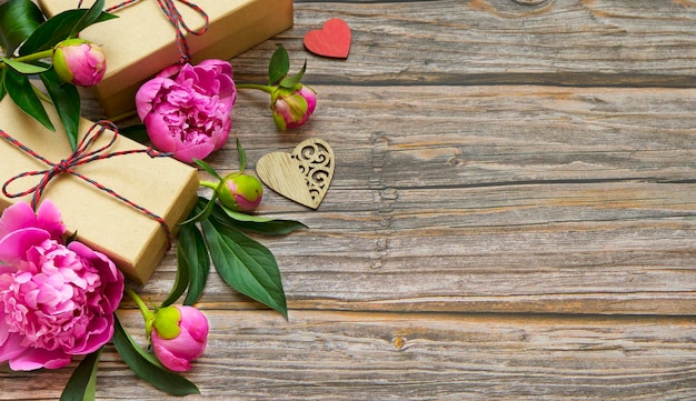 Ремесленные коробки с подарками и цветами пиона на деревянном фоне
