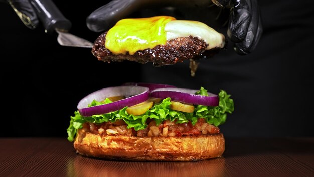 Craft burger is cooking on black background Consist red sauce salsa lettuce red onion pickle cheese chilli green pepper air bun and marbled meat beef Not made ideal Loving hand made