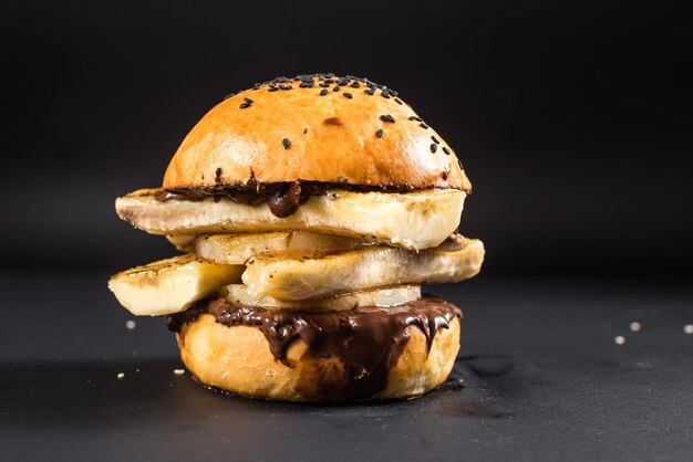 Craft burger with banana and chocolate on the black background