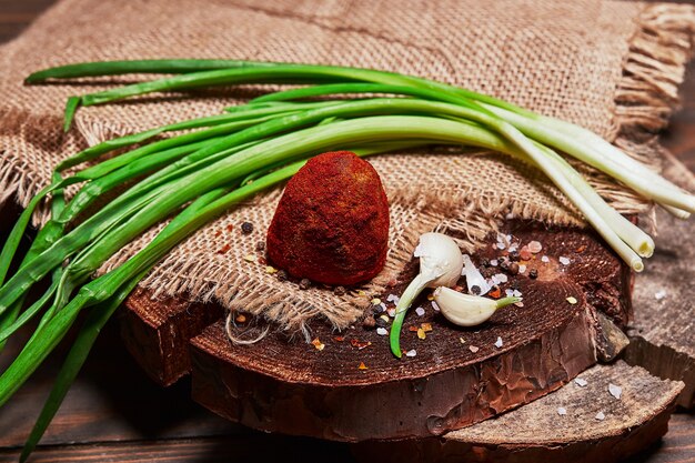 Craft cheese with green onions and garlic cloves on a cloth on a wooden board