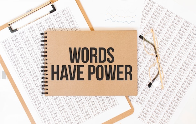 テキスト付きのクラフトカラーメモ帳WordsHave Power Notepad with eyeglasses and textdocuments。ビジネスコンセプト