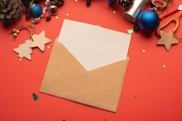 빨간색 배경에 빈 종이와 크리스마스 장식이 있는 공예 봉투