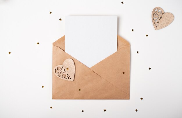 Craft envelope with blank sheet of paper inside and wooden hearts with little golden stars