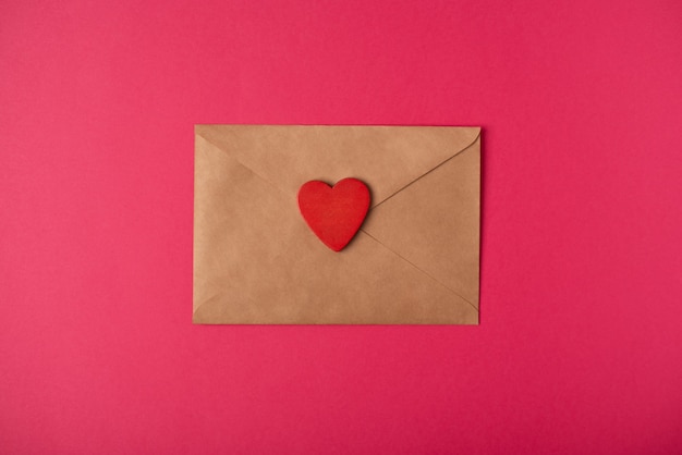 The craft envelope with red heart on the hot pink background. Valentine's Day concept.