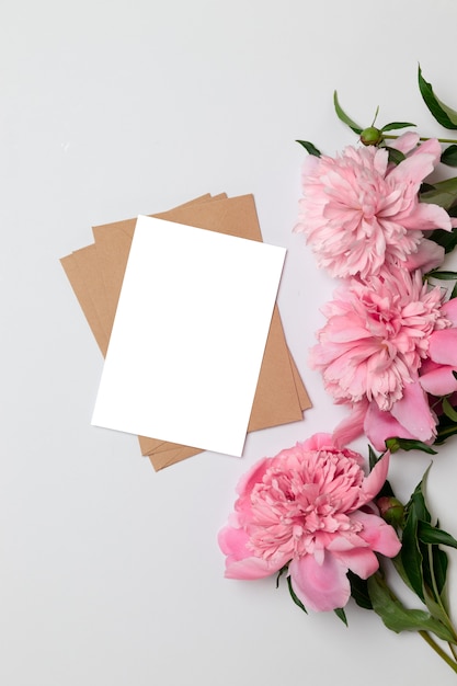 Craft envelope with a sheet of paper with a bouquet of pink peonies on gray 