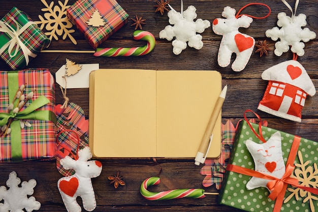 Photo craft notebook on the wooden table decorated for christmas with gifts sweets. top view