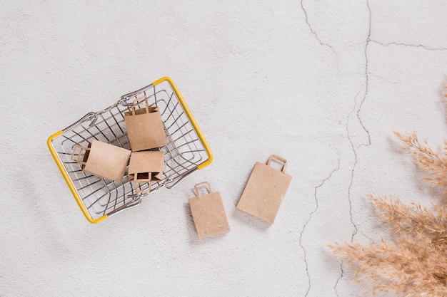 Craft paper bags for shopping in the basket and next to it on a concrete background Top view