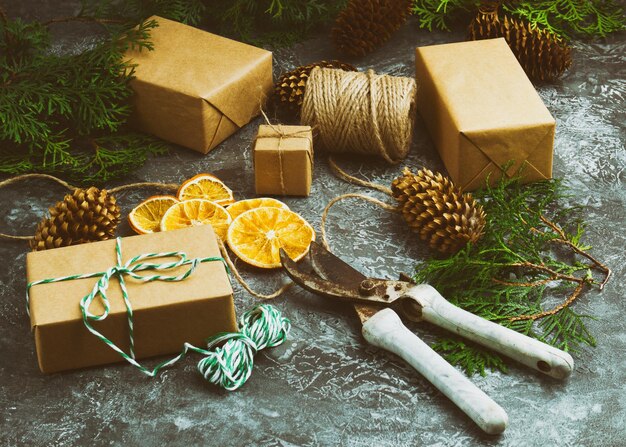 Craft Paper Presents Boxes Cord Fir Tree Branch Dry Sliced Orange Fruit on Concrete Background. Christmas Gift Top View.